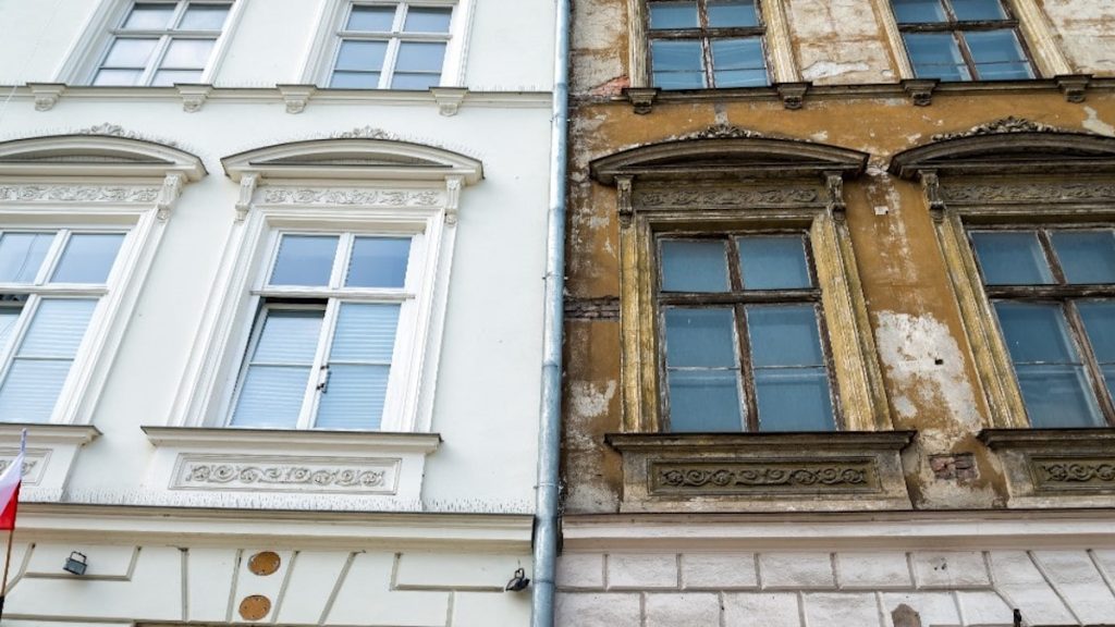 Een gevel die voor de helft gerenoveerd is. Op de linkerzijde heeft de sierpleister een lichte kleur, terwijl de sierpleister aan de rechterzijde nog flink vergeeld en versleten is.
