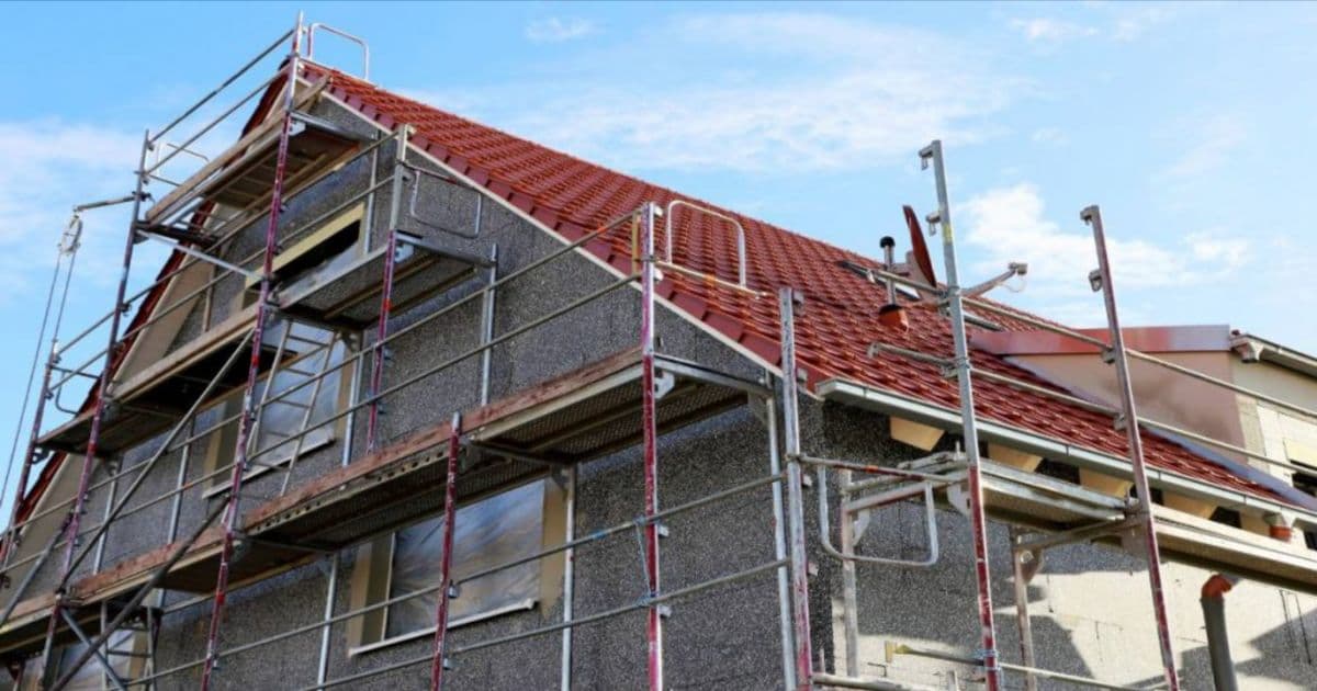 Een huis dat volledig in de steigers staat en waar nog geen pleisterwerk op is aangebracht