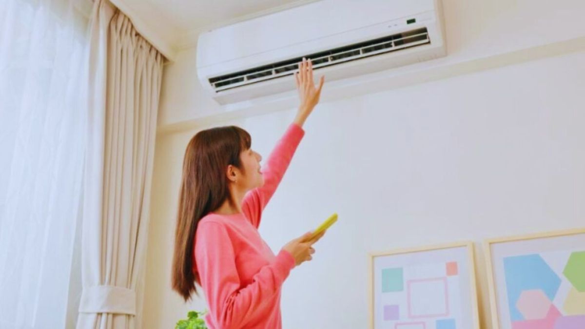 Een vrouw die een airco op temperatuur test