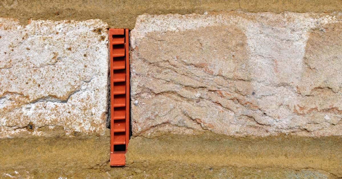 Een oranje stootvoeg is in de voeg van een bakstenen gevel geplaatst