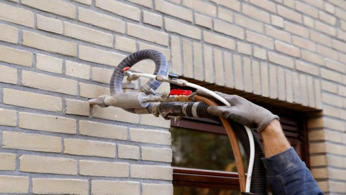 Een vakman is bezig met het aanbrengen van spouwmuurisolatie.