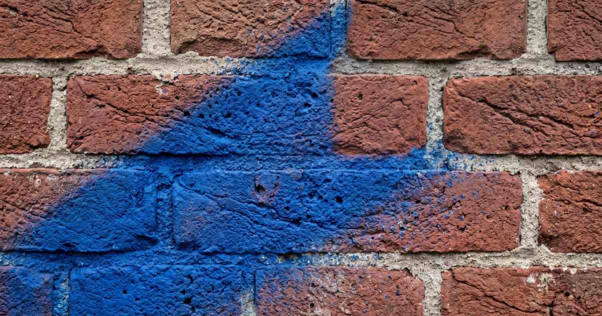 Blauwe spuitverf die in de poriën en de voegen van ruwe baksteen is getrokken