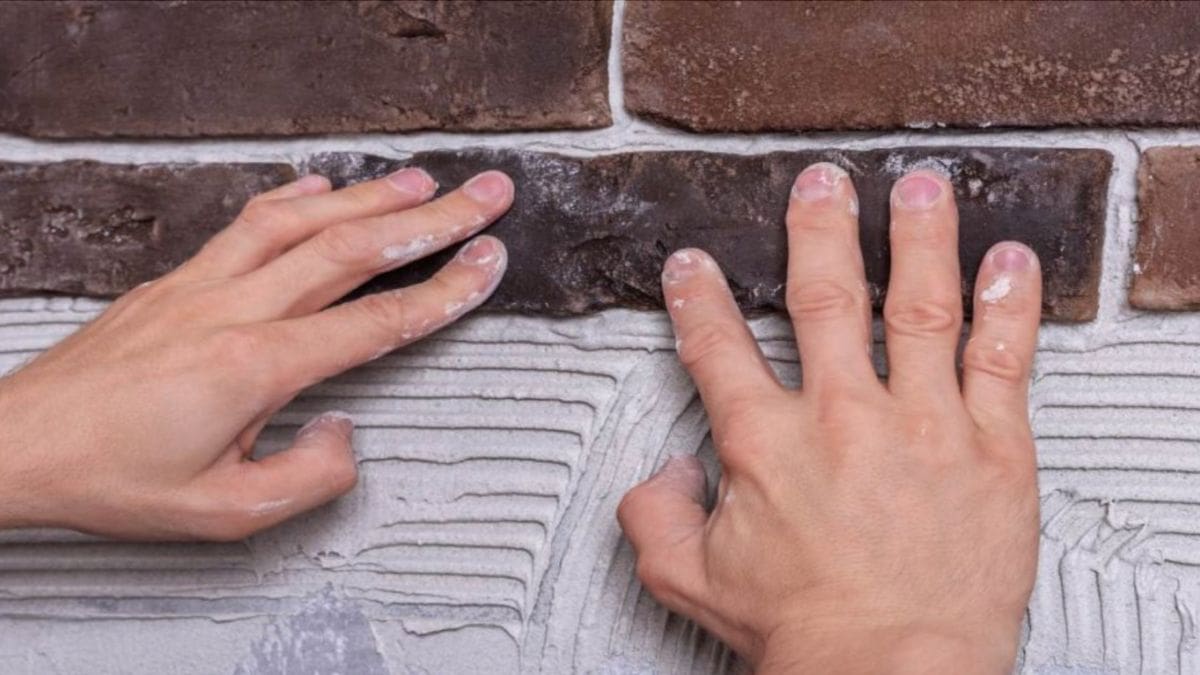 Een gevelspecialist brengt steenstrips aan op een grijze ondergrond