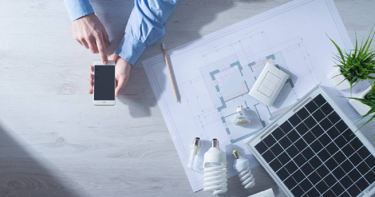 Een man in een blauw hemd gebruikt zijn smartphone om te berekenen hoe lang het duurt voor zijn thuisbatterij zichzelf terugverdient.