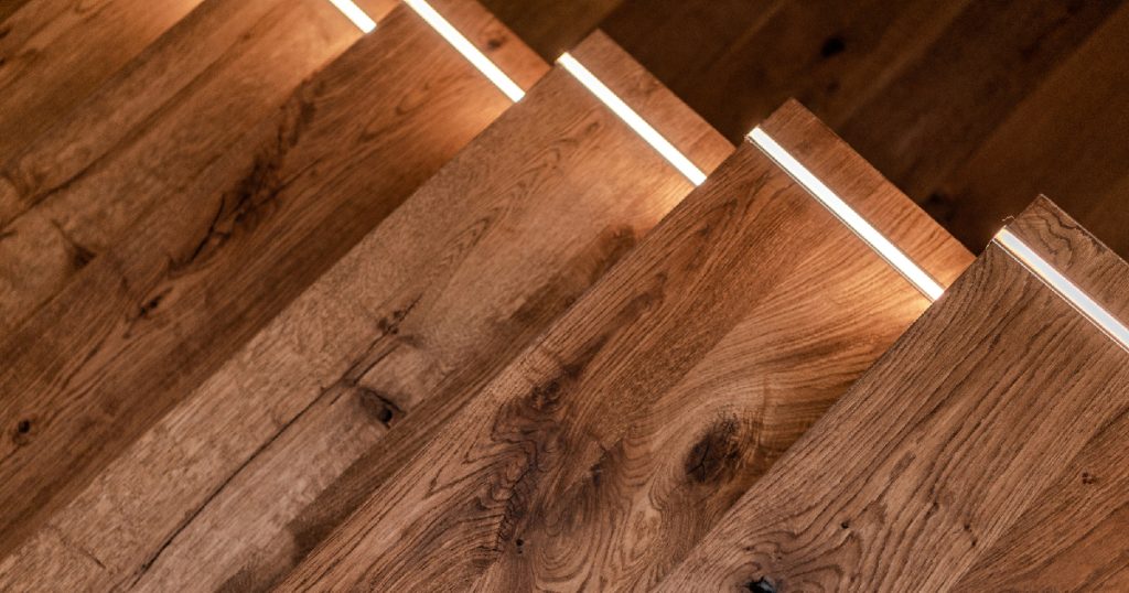 Een houten trap met ingebouwde verlichting behandeld met donkere beits.