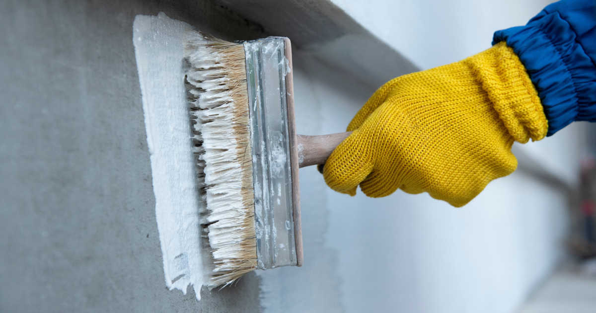 Een laag waterdichte verf wordt op een buitenmuur aangebracht