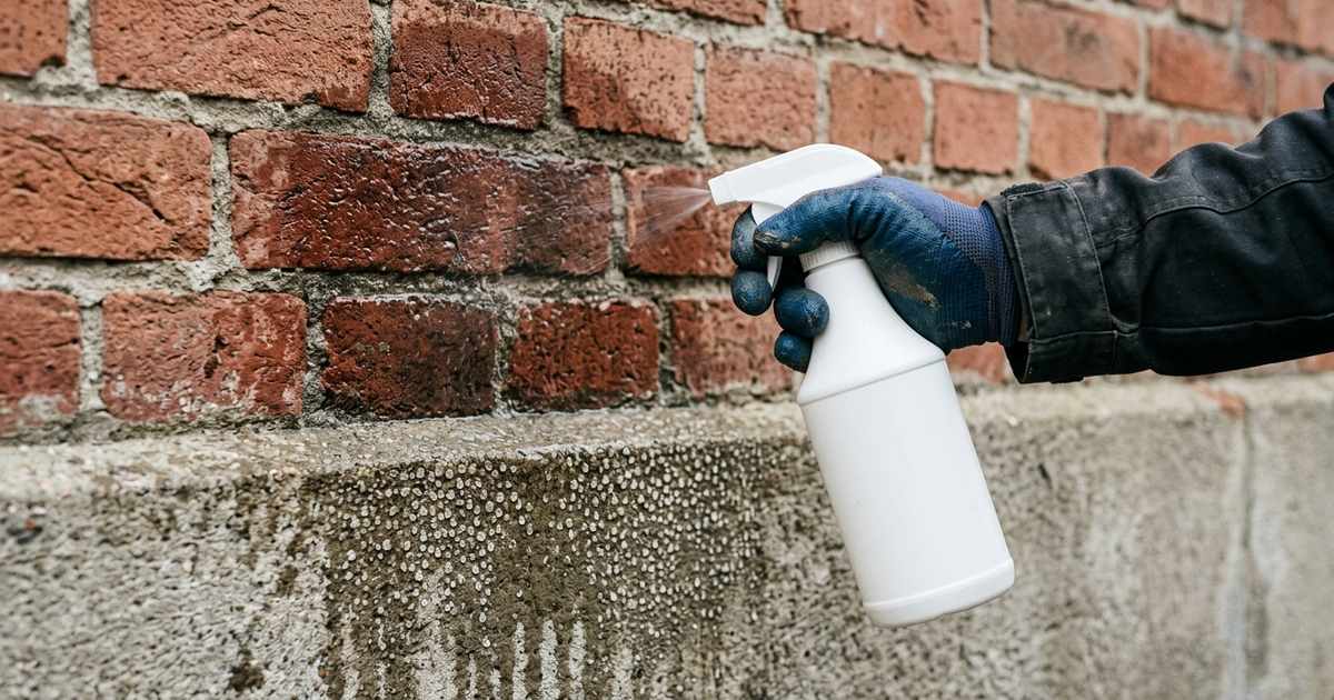 Watertest op een gevel: baksteen zuigt het water op, op de gladde betonplint parelen de druppels