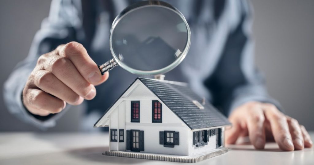 Een man onderzoekt een woning met een vergrootglas.