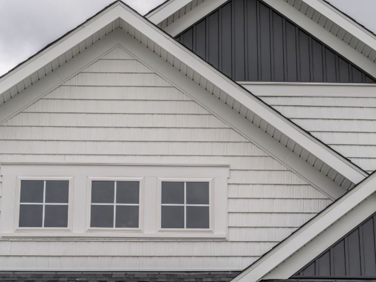 Woning met witte en grijze kunststof gevelbekleding in overlappende panelen en klassieke uitstraling.