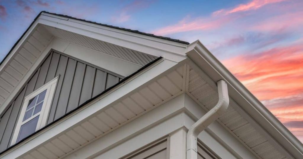 Woning met grijze PVC-gevelbekleding en witte afwerking bij zonsondergang.