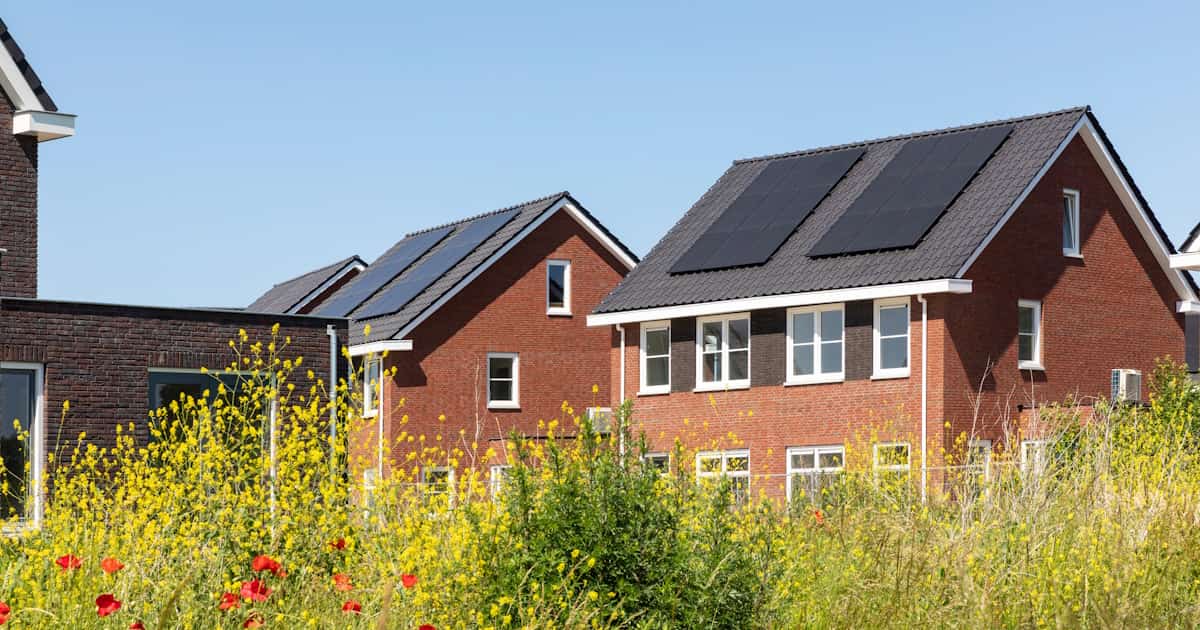 Nederlandse woningen met een bakstenen gevel en een zadeldak met dakpannen. Op het dak liggen zonnepanelen
