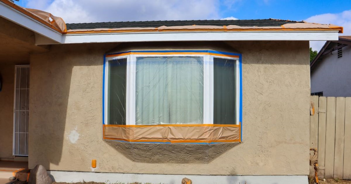 Voordat je de gevel schoonmaakt is het verstandig om deuren en ramen af te plakken. Op de foto is de klus goed voorbereid.