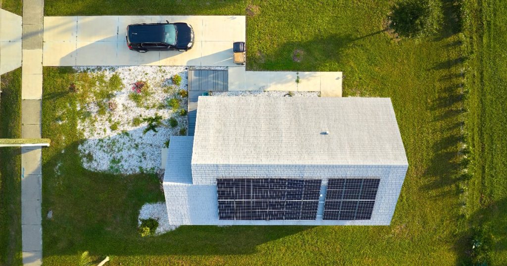 Bovenaanzicht van een woning met een grote tuin en een dak met zonnepanelen.